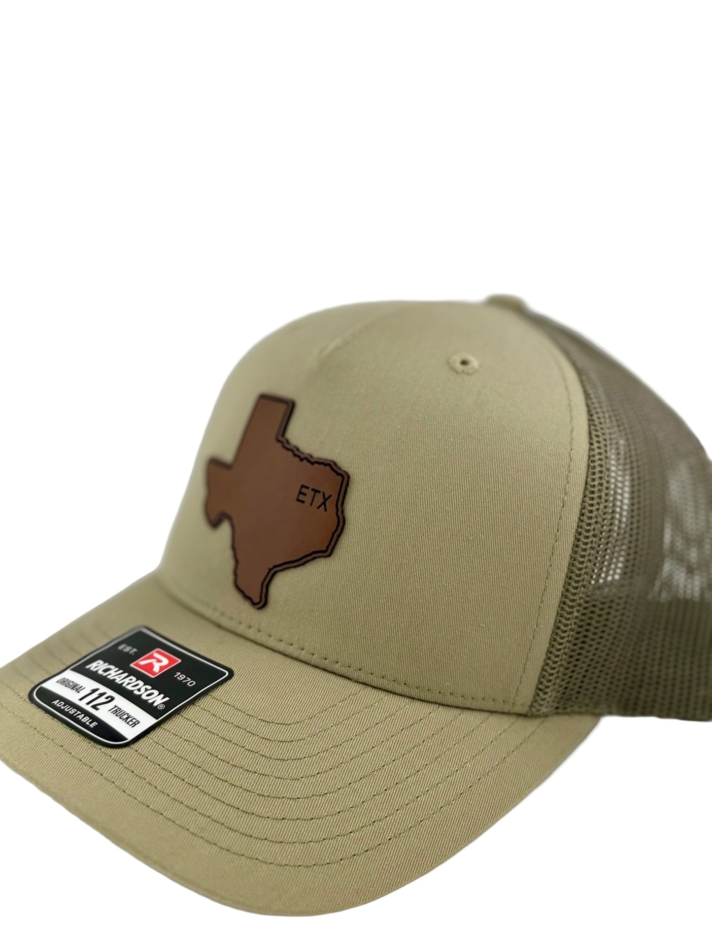"Side view of a khaki trucker hat with a matching mesh back and structured front panel. The brown Texas-shaped patch with the embossed 'ETX' stands out, giving a rustic and regional aesthetic. A Richardson 112 label is visible on the brim."