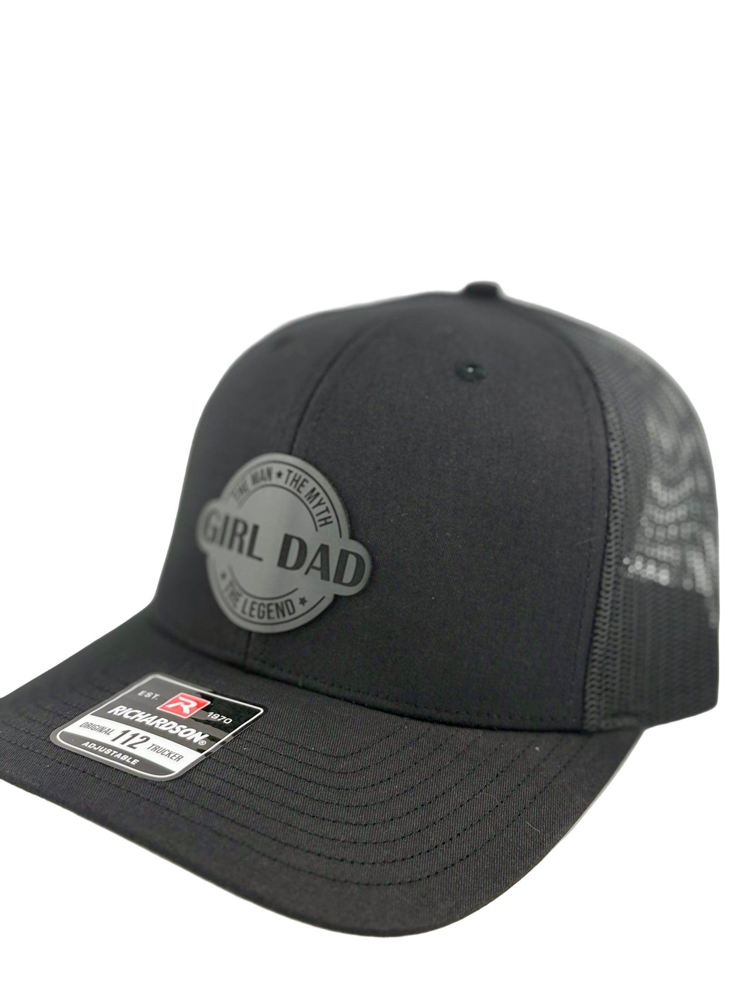 "Side view of a black trucker hat with a black mesh back and structured front panel. The circular gray patch with 'GIRL DAD' and the phrases 'The Man • The Myth • The Legend' gives the hat a sleek, modern, and proud fatherhood aesthetic. A Richardson 112 label is visible on the brim."